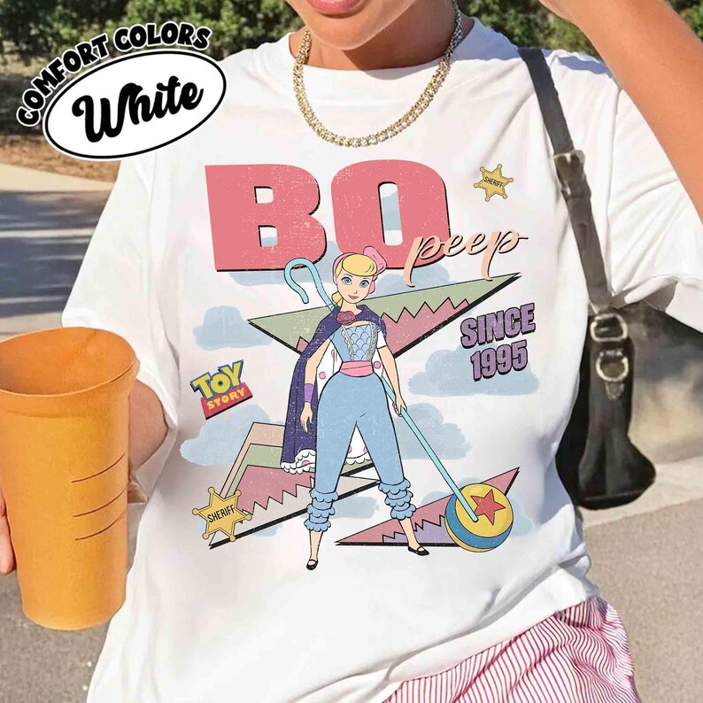 May include: White t-shirt featuring a graphic of Bo Peep from Toy Story, with the text "BO PEEP" and "SINCE 1995". The design includes a cartoon illustration of Bo Peep with her staff and a sheriff badge.