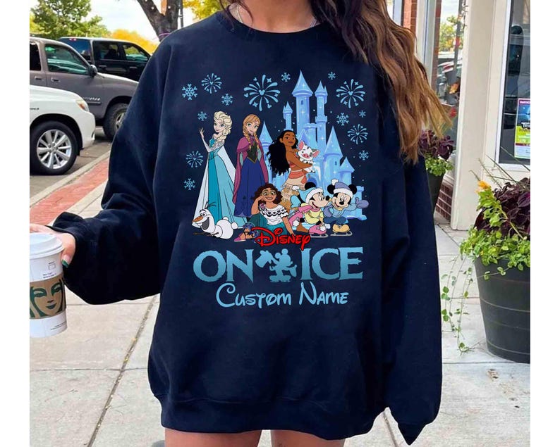 Puede incluir: Sudadera azul marino con personajes de Disney sobre hielo. El dise&ntilde;o incluye a Elsa, Anna, Moana, Mickey y Minnie Mouse, con un castillo y fuegos artificiales. El texto "Disney ON ICE Custom Name" est&aacute; impreso en azul claro.