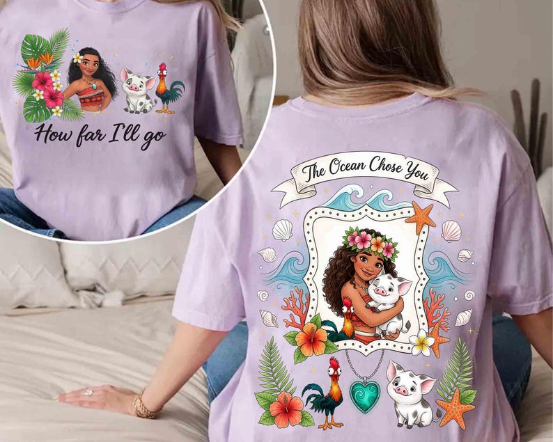 Op de afbeelding: Lichtpaars T-shirt met een cartoon illustratie van een vrouw, een varken en een haan. De voorkant van het shirt heeft de tekst "How far I'll go". De achterkant van het shirt zegt "The Ocean Chose You".