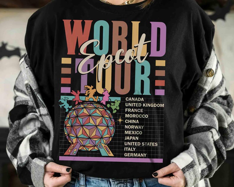 K&ouml;nnte beinhalten: Schwarzes T-Shirt mit einer bunten Grafik des Epcot World Showcase. Die Grafik enth&auml;lt den Text "World Epcot Tour" und eine Liste der im World Showcase vertretenen L&auml;nder: Kanada, Vereinigtes K&ouml;nigreich, Frankreich, Marokko, China, Norwegen, Mexiko, Japan, Vereinigte Staaten, Italien und Deutschland.