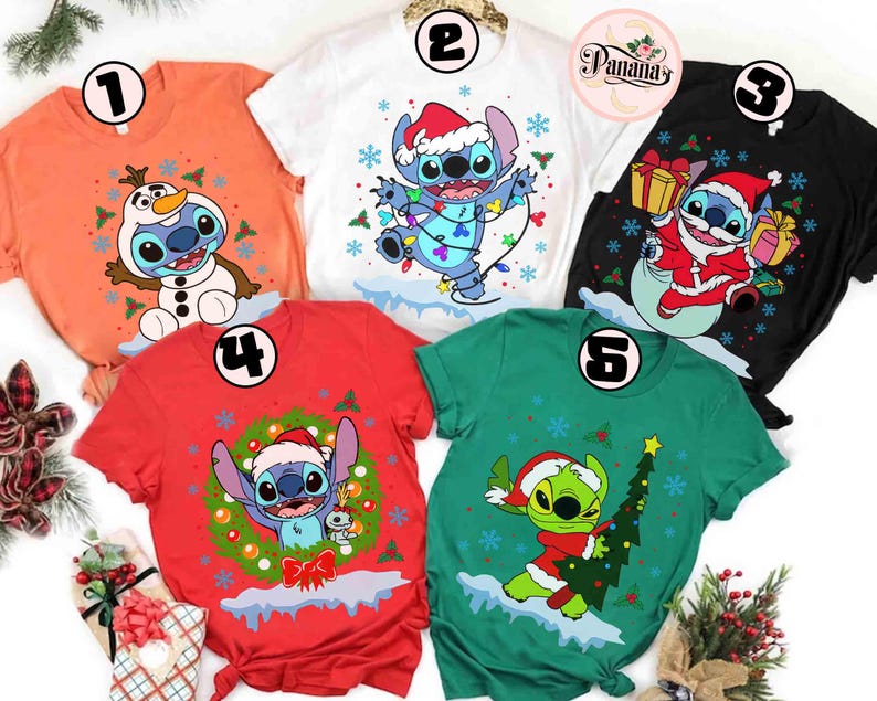 May include: A collection of five short-sleeved t-shirts featuring holiday-themed cartoon character designs. The shirts are in various colors, including orange, white, black, red, and green. Each shirt showcases a different festive graphic, such as a character in a Santa hat or with a Christmas tree.