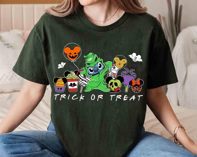 May include: Dark green t-shirt with a Halloween-themed graphic. The design features a green character holding a balloon, surrounded by cartoon treats and the words "TRICK OR TREAT" in white. The shirt is a casual, short-sleeved style.