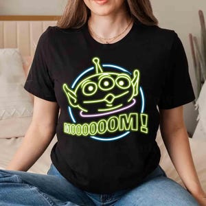 May include: Black t-shirt with a neon green alien character and the text "Mooooom!" in neon green and yellow.