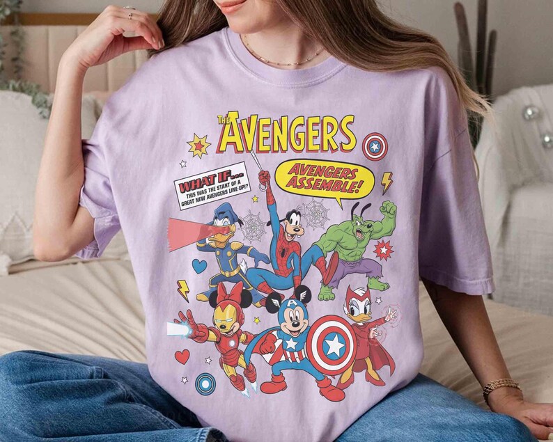 May include: A lilac t-shirt with a comic-style illustration of The Avengers characters, including Mickey Mouse as Captain America, Spider-Man, and Donald Duck. The text "The Avengers" and "Avengers Assemble!" are also displayed.
