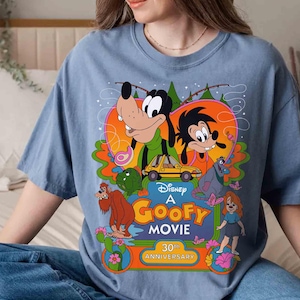 May include: A blue t-shirt with a graphic of Goofy and other Disney characters from the movie "A Goofy Movie". The graphic includes the text "Disney A Goofy Movie 30th Anniversary".