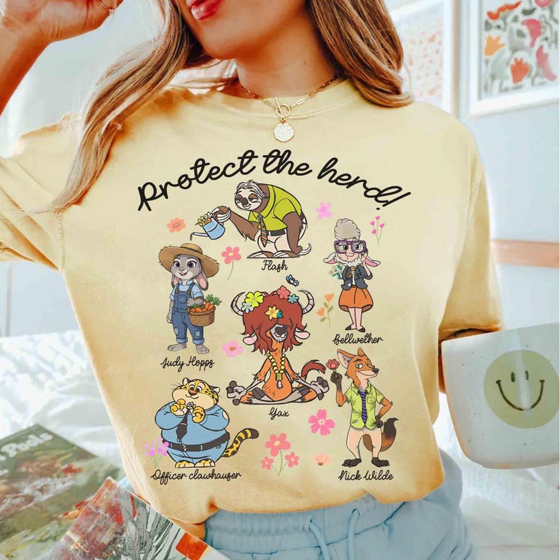 Peut inclure: T-shirt jaune avec une illustration de personnages de dessin anim&eacute; du film Zootopia. Le texte "Protect the herd!" est imprim&eacute; sur le t-shirt. Les personnages incluent Judy Hopps, Nick Wilde, Flash, Yax, Bellwether et Officer Clawhauser.