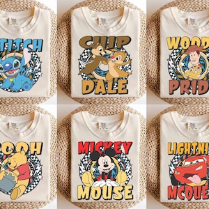 May include: Six cream-colored t-shirts featuring Disney characters. Each shirt has a different character design: Stitch, Chip and Dale, Woody, Pooh, Mickey Mouse, and Lightning McQueen. The designs are in a circular graphic with the character's name.