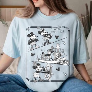 Może przedstawiać: Jasnoniebieska koszulka z czarno-białą grafiką Myszki Miki ze Steamboat Willie. Grafika przedstawia Myszkę Miki w r&oacute;żnych scenach z filmu z 1928 roku, z napisem "Steamboat Willie EST. 1928".