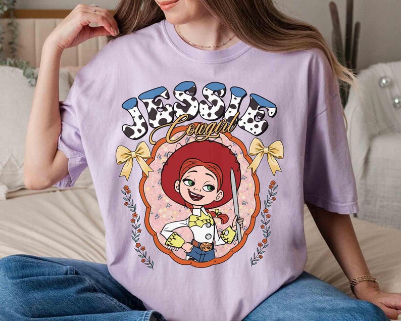 May include: Purple t-shirt with a cartoon image of Jessie from Toy Story. The shirt has the text "Jessie Cowgirl" in a colorful font.