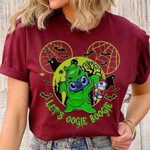 May include: Burgundy t-shirt featuring a green Oogie Boogie-inspired Stitch character holding a rag doll. The design includes bats, spiderwebs, and the text "Let's Oogie Boogie" in green, with a Mickey Mouse ear silhouette.