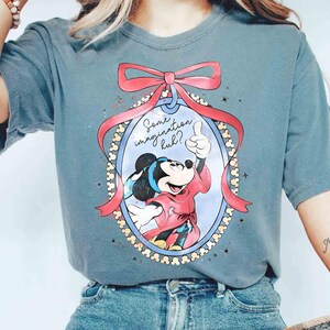 May include: A blue t-shirt with a Mickey Mouse cartoon design. Mickey is in a red outfit, giving a thumbs-up within an oval frame, a pink bow, and the text "Some imagination huh?"