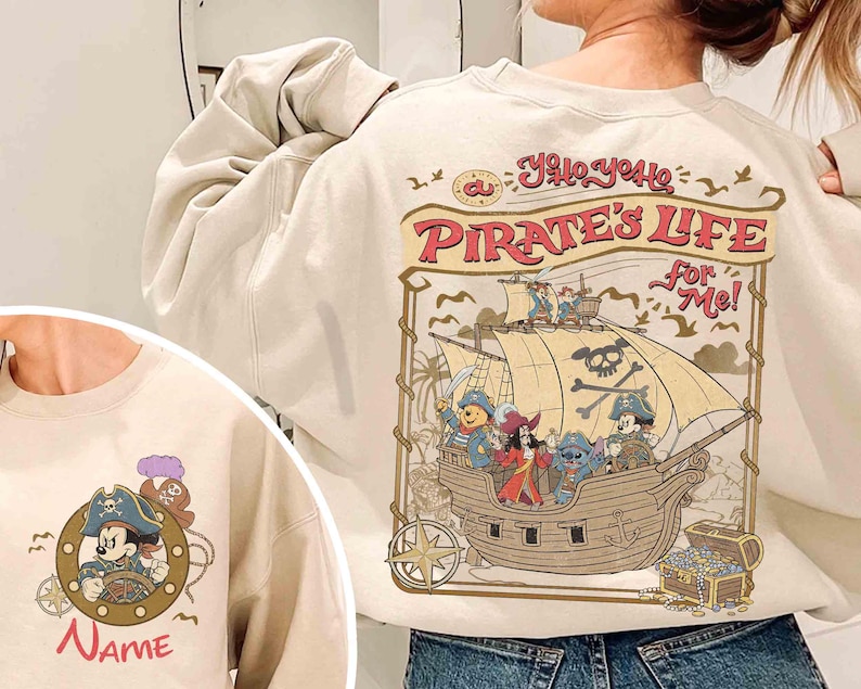 K&ouml;nnte beinhalten: Cremefarbenes Sweatshirt mit einem Piratenschiff-Design mit Disney-Figuren. Auf der R&uuml;ckseite des Sweatshirts steht der Text "Yo Ho, Yo Ho, A Pirate's Life For Me!". Auf der Vorderseite befindet sich ein Mickey Mouse Piraten-Design mit dem Wort "Name".