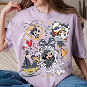 Puede incluir: Una camiseta lila claro con gr&aacute;ficos de Disney con tem&aacute;tica de graduaci&oacute;n. Mickey Mouse, Donald Duck y Goofy est&aacute;n representados con atuendos de graduaci&oacute;n. El dise&ntilde;o incluye globos, diplomas y una taza de t&eacute; con corazones.