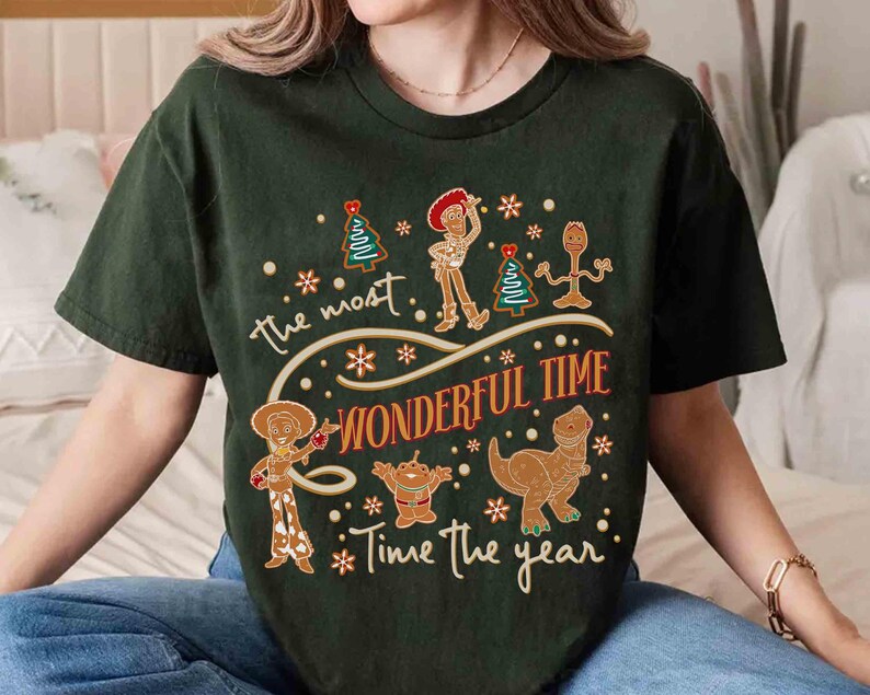 Puede incluir: Camiseta verde oscuro con un dise&ntilde;o festivo. El texto dice "the most WONDERFUL TIME Time the year". El dise&ntilde;o incluye personajes de dibujos animados, copos de nieve y &aacute;rboles de Navidad. Una camiseta navide&ntilde;a divertida y caprichosa.