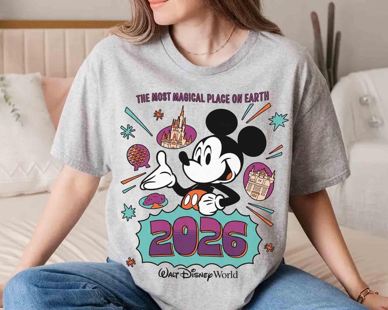 May include: A grey t-shirt with a Mickey Mouse design, the text reads "THE MOST MAGICAL PLACE ON EARTH" and "2026 Walt Disney World". The design includes Disney landmarks and colourful accents.