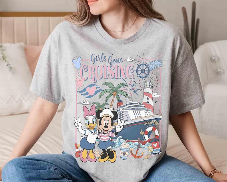 Peut inclure: T-shirt gris avec l'inscription "Girls Gone Cruising" et un motif de bateau de croisi&egrave;re, phare, palmiers et personnages de dessins anim&eacute;s. Minnie et Daisy Duck font le signe de la paix.
