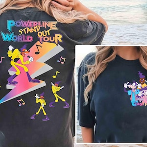 May include: Two black t-shirts with different cartoon character designs. The first shirt features a cartoon character in a purple and yellow outfit standing on a lightning bolt with the text "Powerline Stand Out World Tour". The second shirt features a group of cartoon characters with the text "Goofy".