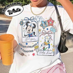 May include: White t-shirt with a graphic featuring Minnie Mouse and Daisy Duck in sailor outfits. The shirt includes the text "BESTFRIEND FOREVER" and "Minnie Mouse" and "Daisy Duck" in cursive.