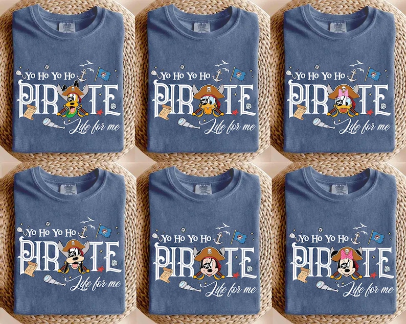 Peut inclure: Six t-shirts bleus avec un th&egrave;me de pirate. Chaque t-shirt pr&eacute;sente un personnage de dessin anim&eacute; diff&eacute;rent portant un chapeau de pirate, le mot "PIRATE" et la phrase "Life for me". Les t-shirts sont dispos&eacute;s sur une surface tiss&eacute;e.