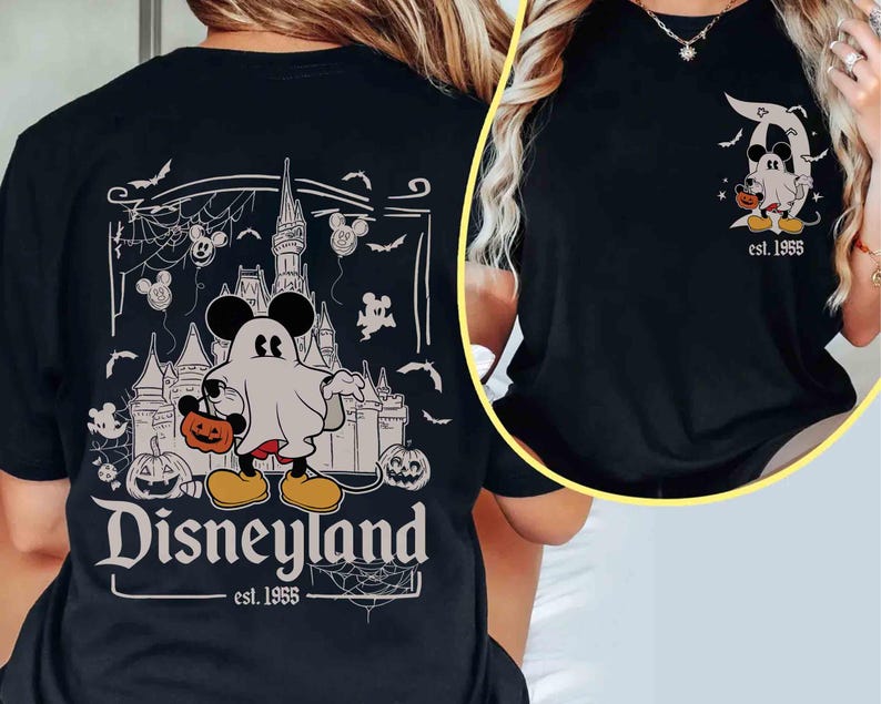 May include: Black t-shirt with a Disneyland Halloween design. The graphic shows Mickey Mouse as a ghost with a pumpkin, a castle, and the text "Disneyland est. 1955". The design also includes bats and Mickey Mouse balloons.