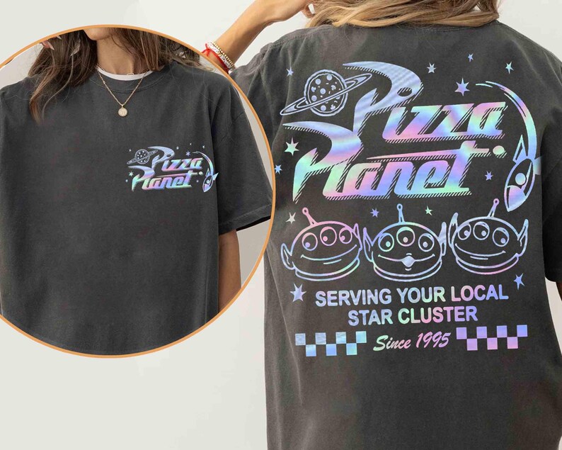 May include: Dark gray t-shirt with a Pizza Planet logo on the front and back. The back features the Pizza Planet logo, three alien characters, and the text "Serving Your Local Star Cluster Since 1995" in a holographic design.
