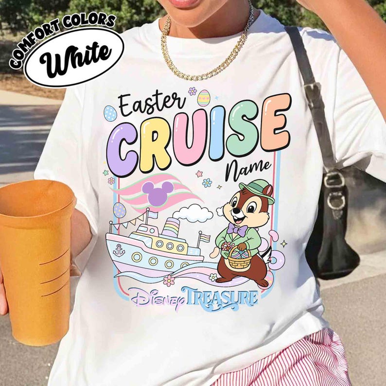 K&ouml;nnte beinhalten: Wei&szlig;es T-Shirt mit dem Aufdruck "Easter Cruise" in Pastellfarben, einem Cartoon-Schiff und einem Chip-Charakter mit einem Korb. Das Shirt tr&auml;gt auch die Aufschrift "Disney Treasure".