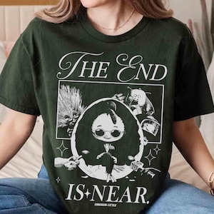 Puede incluir: Camiseta verde oscuro con el texto "The End Is Near" en escritura blanca. El gráfico presenta un pollo de dibujos animados con gafas dentro de un marco ovalado, con otros personajes y estrellas. Las palabras "Chicken Little" están en la parte inferior.