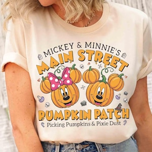 May include: Cream-colored t-shirt featuring a pumpkin design with Mickey and Minnie Mouse ears. The shirt has the text "Mickey & Minnie's Main Street Pumpkin Patch" with additional text "Picking Pumpkins & Pixie Dust".