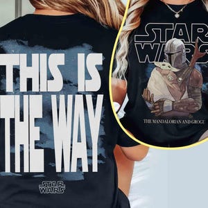 May include: A black t-shirt featuring a large white graphic on the back that reads THIS IS THE WAY with a blue brushstroke background. The front graphic displays the Star Wars logo, The Mandalorian and Grogu, and the text The Mandalorian and Grogu.