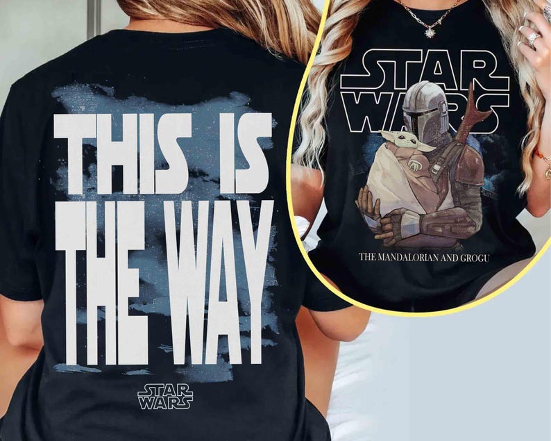May include: A black t-shirt featuring a large white graphic on the back that reads THIS IS THE WAY with a blue brushstroke background. The front graphic displays the Star Wars logo, The Mandalorian and Grogu, and the text The Mandalorian and Grogu.