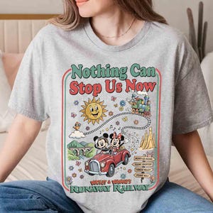 Peut inclure: Un t-shirt gris avec un motif color&eacute; affichant le texte "Nothing Can Stop Us Now". Le motif comprend Mickey et Minnie Mouse dans une voiture rouge, un soleil souriant et un train. Le t-shirt a un col rond et des manches courtes.