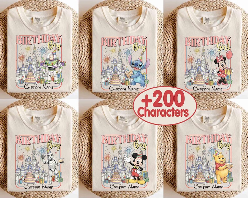May include: Cream-colored t-shirts with colorful graphic designs featuring Disney characters and the text "BIRTHDAY Boy" or "BIRTHDAY Girl". Each shirt has a castle illustration, fireworks, and space for a custom name. The shirts are folded on woven mats.