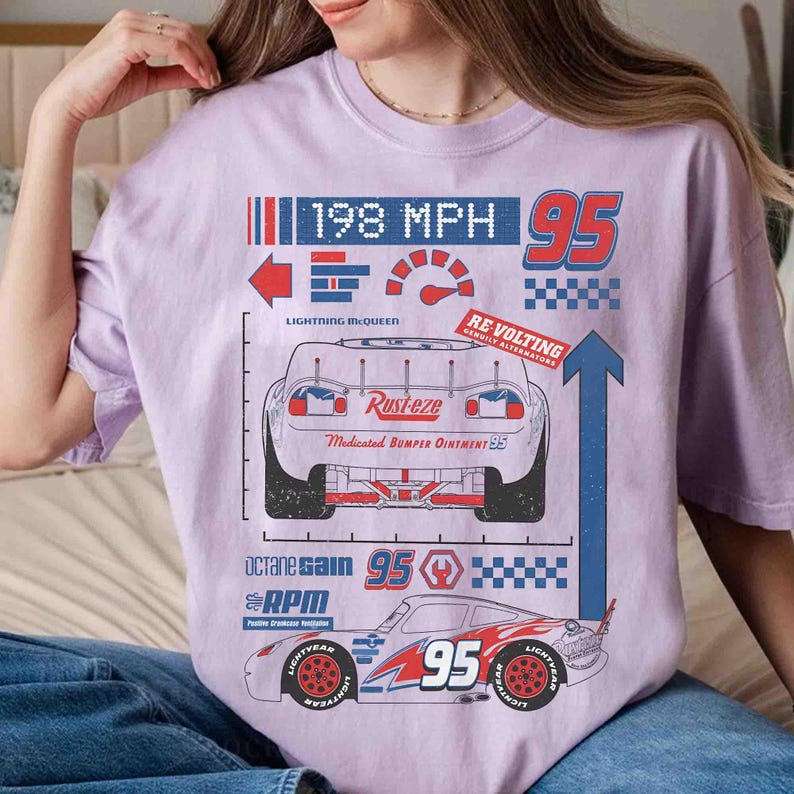 K&ouml;nnte beinhalten: Ein hellviolettes T-Shirt mit einem Grafikdruck eines Rennwagens mit der Nummer 95, dem Text 198 MPH, Rust-eze, Re-Volting, Octane Gain und RPM. Das Design enth&auml;lt einen Tachometer, Karomuster sowie rote, blaue und wei&szlig;e Pfeile.