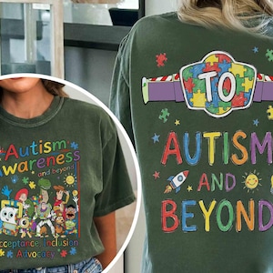May include: Olive green t-shirt with the words "Autism Awareness and beyond" in colorful letters. The front features cartoon characters and the words "Acceptance, Inclusion, Advocacy". The back says "Autism and Beyond" with a puzzle piece design.