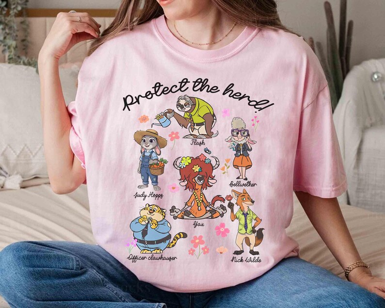 Peut inclure: T-shirt rose avec un graphique de personnages du film Zootopia. Le texte "Protect the herd!" est imprim&eacute; sur le t-shirt. Les personnages incluent Judy Hopps, Nick Wilde, Flash, Bellwether, Yax et Officer Clawhauser.