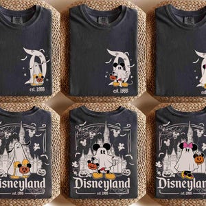 May include: Six dark grey t-shirts featuring Halloween-themed Disneyland designs. The graphics include Mickey and Minnie Mouse as ghosts, holding pumpkins, and the Disneyland logo. The text "est. 1955" is also visible.