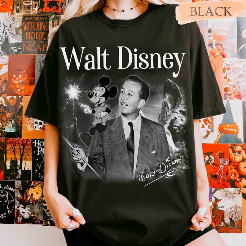 Puede incluir: Una camiseta negra con un estampado gr&aacute;fico de Walt Disney en traje y corbata, con un peque&ntilde;o personaje de Mickey Mouse sobre su hombro. El texto Walt Disney est&aacute; impreso en una fuente serif blanca sobre la imagen, con una firma debajo.