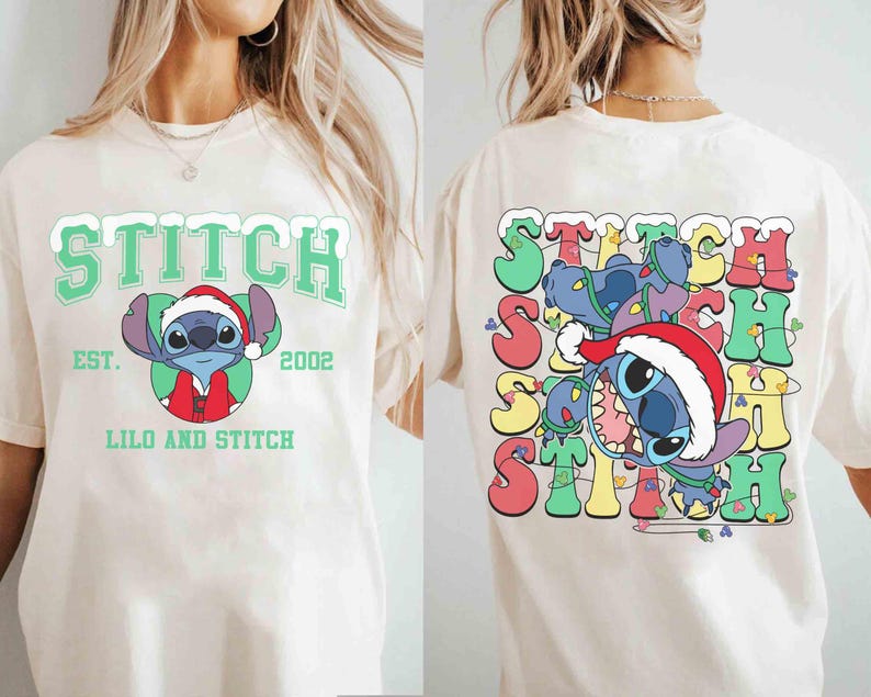 May include: Cream-colored t-shirt featuring a front graphic of Stitch wearing a Santa hat, with the text "STITCH" above and "LILO AND STITCH" below. The back of the shirt shows Stitch tangled in Christmas lights, with the word "STITCH" repeated.
