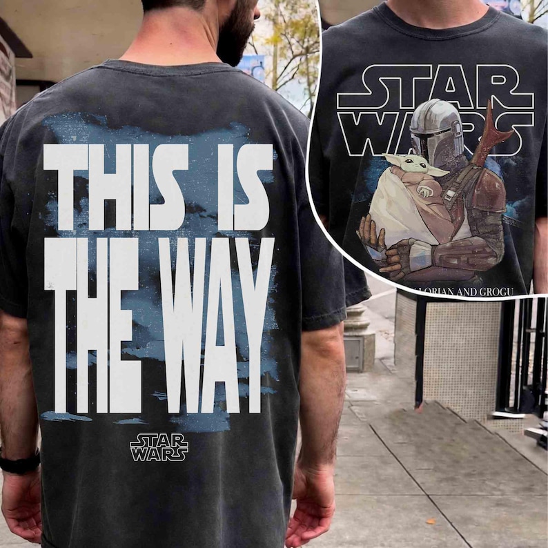 May include: A charcoal gray short-sleeve t-shirt featuring a large white graphic on the back that reads THIS IS THE WAY with a Star Wars logo. The front displays a graphic of The Mandalorian holding Grogu with the text STAR WARS above them.