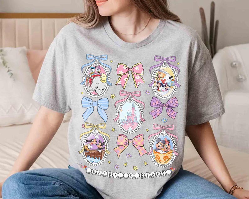 May include: A gray t-shirt with a graphic print of Disney characters in oval frames with pink bows and pastel colors. The text "Original to Timeless" is printed on the bottom of the shirt.