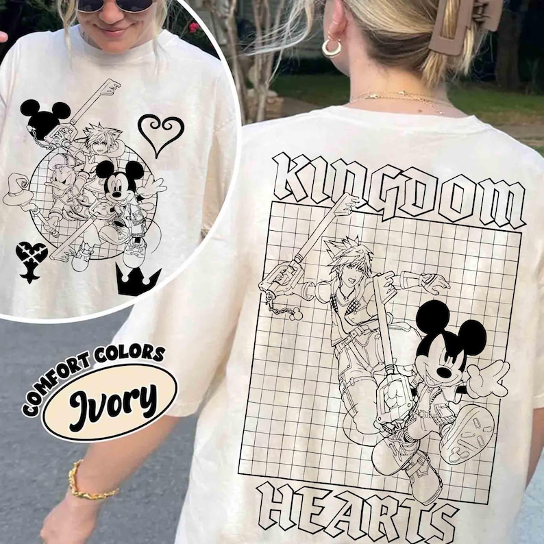 Puede incluir: Camiseta color marfil con gr&aacute;ficos en blanco y negro de Kingdom Hearts. La parte delantera presenta un dise&ntilde;o circular con personajes y s&iacute;mbolos. La parte trasera muestra el texto "KINGDOM HEARTS". La camiseta es de Comfort Colors.