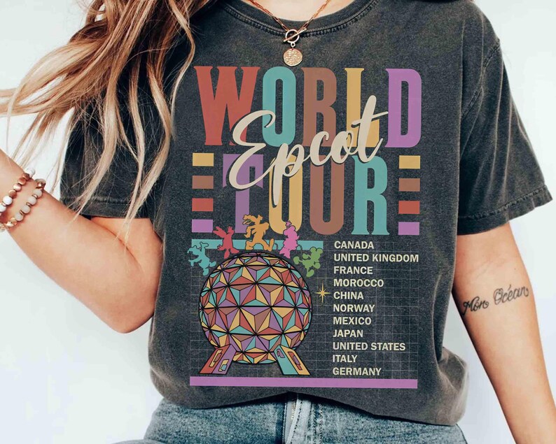 K&ouml;nnte beinhalten: Ein schwarzes T-Shirt mit einer Grafik im Vintage-Stil, die "World Epcot Tour" in bunten Buchstaben zeigt. Die Grafik zeigt auch ein stilisiertes Bild der Epcot Spaceship Earth und eine Liste der im Park vertretenen L&auml;nder.