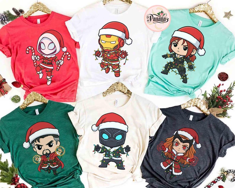 May include: A collection of Christmas-themed t-shirts featuring various Marvel characters in Santa hats and festive attire. The shirts are in red, white, green, and teal, with character designs including Spider-Man, Iron Man, Black Widow, Doctor Strange, Black Panther, and Scarlet Witch.