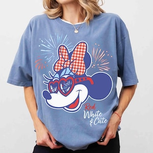 Op de afbeelding: Lichtblauw T-shirt met een cartoon muis ontwerp. De muis heeft een rood-witte ruitjesstrik, hartvormige zonnebril en vuurwerk. De tekst "Red White & Cute" is cursief geschreven. Het T-shirt heeft korte mouwen.