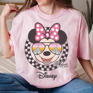 May include: Pink t-shirt with a graphic of Mickey Mouse wearing sunglasses with the words "Disney" and "Minnie Mouse xoxo" printed on the front.