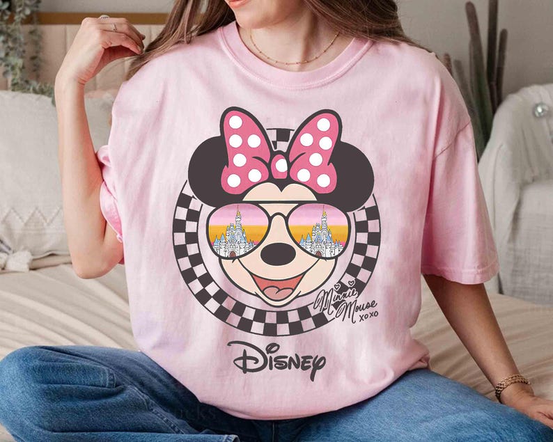 May include: Pink t-shirt with a graphic of Mickey Mouse wearing sunglasses with the words "Disney" and "Minnie Mouse xoxo" printed on the front.