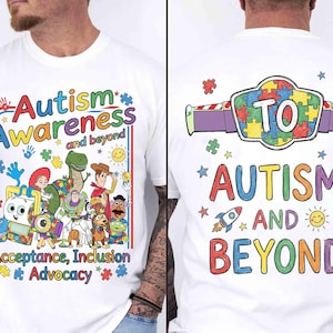 May include: White t-shirt with colorful text and graphics promoting autism awareness. The front features the words "Autism Awareness and beyond" with cartoon characters. The back says "TO Autism and Beyond".