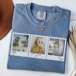 May include: A blue Comfort Colors t-shirt with three polaroid-style photos printed on the front. The photos feature women in sunglasses. The words "gold's gone" are written on the middle photo. A gold necklace is draped across the shirt.