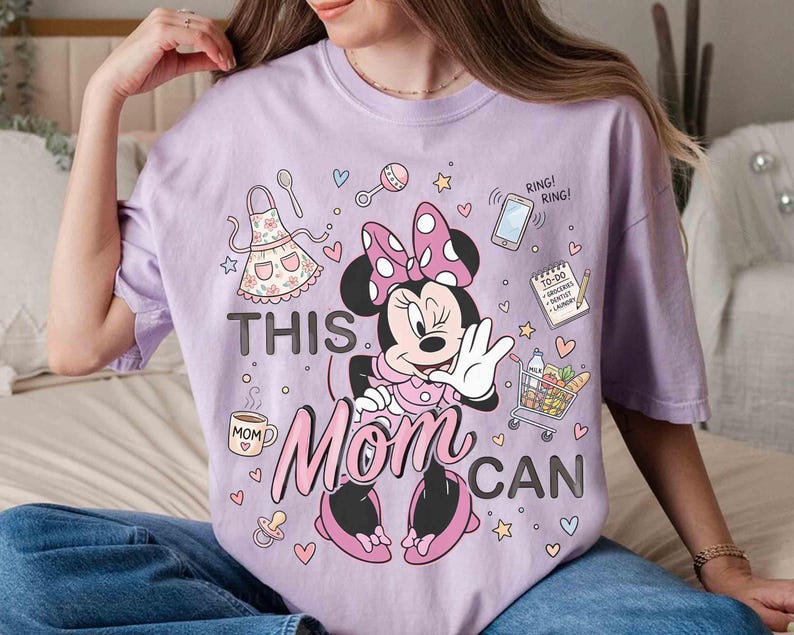K&ouml;nnte beinhalten: Helllila T-Shirt mit Minnie Mouse und dem Text "THIS MOM CAN". Das Design beinhaltet einen Einkaufswagen, ein Telefon, eine To-Do-Liste und andere Symbole. Das Shirt ist ein l&auml;ssiger Stil.