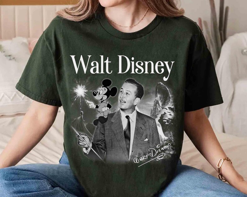 Puede incluir: Una camiseta de manga corta de color verde oscuro con un estampado gr&aacute;fico de Walt Disney y Mickey Mouse. El dise&ntilde;o incluye el texto Walt Disney en la parte superior, una imagen en blanco y negro de Walt Disney, una peque&ntilde;a figura de Mickey y una firma.